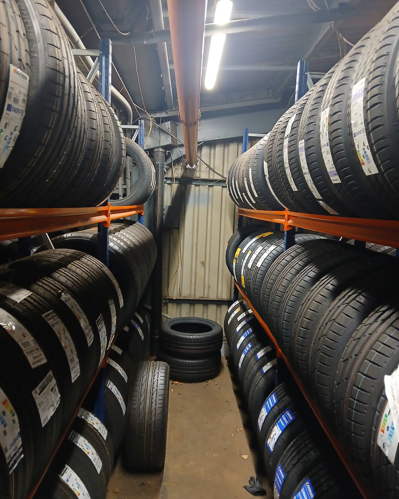 Looking down an aisle of tyre racking, both sides stacked with new tyres on their rails