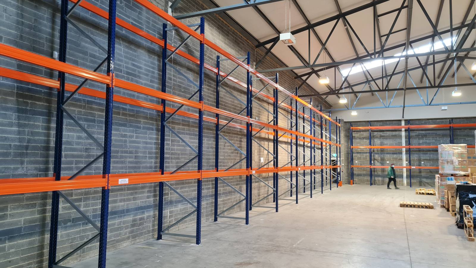 Adjustable pallet racking bays in a warehouse, blue frames with orange beams