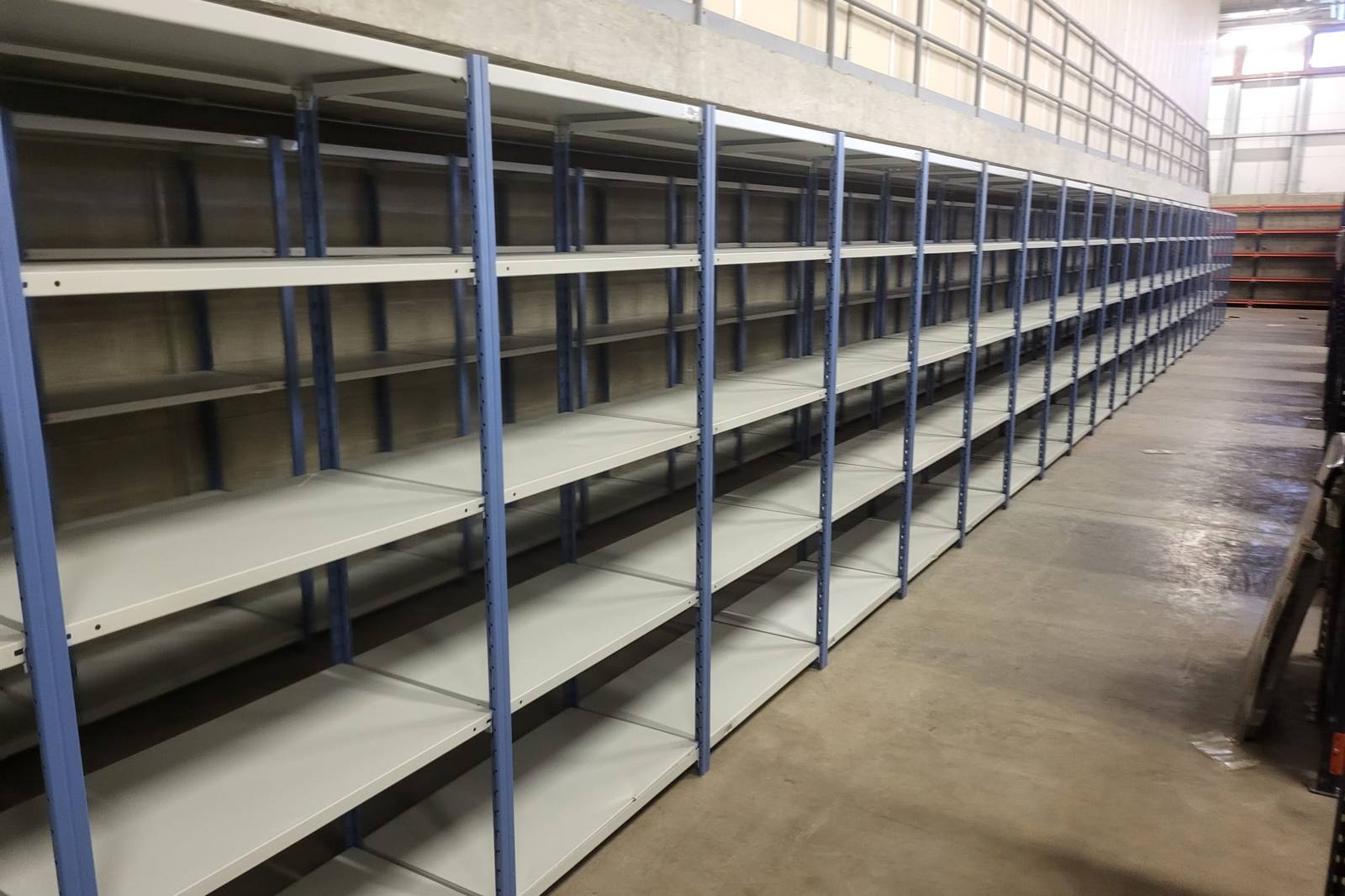 Run of grey modular shelving bays with blue uprights