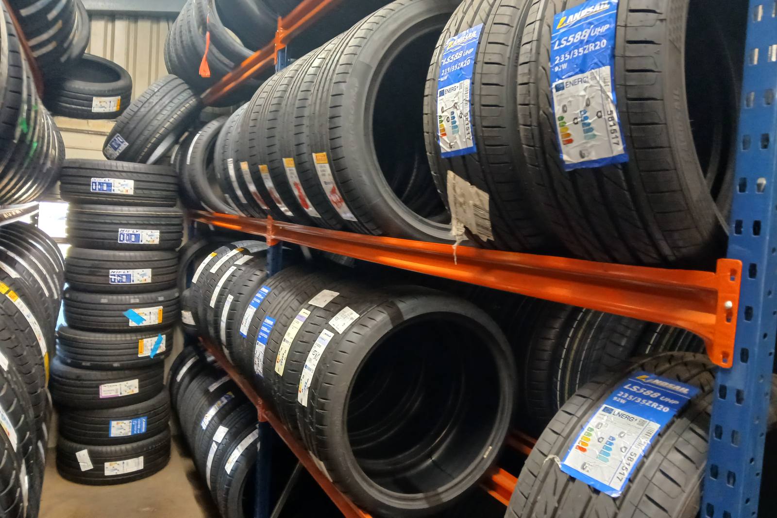 Tyre racking bays with blue uprights and orange rails, loaded with new car tyres